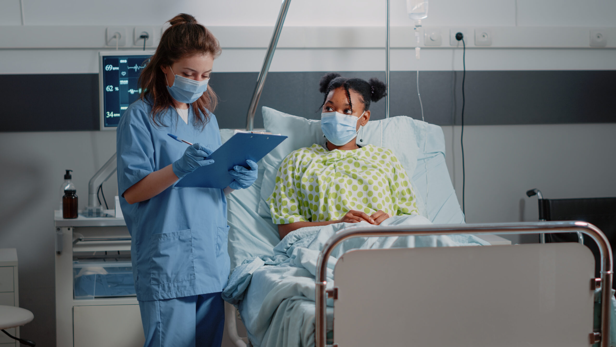 medical-assistant-doing-consultation-with-ill-patient-wearing-face-masks-hospital-ward-nurse-discussing-with-young-woman-about-healthcare-treatment-taking-notes-during-pandemic-scaled.jpg